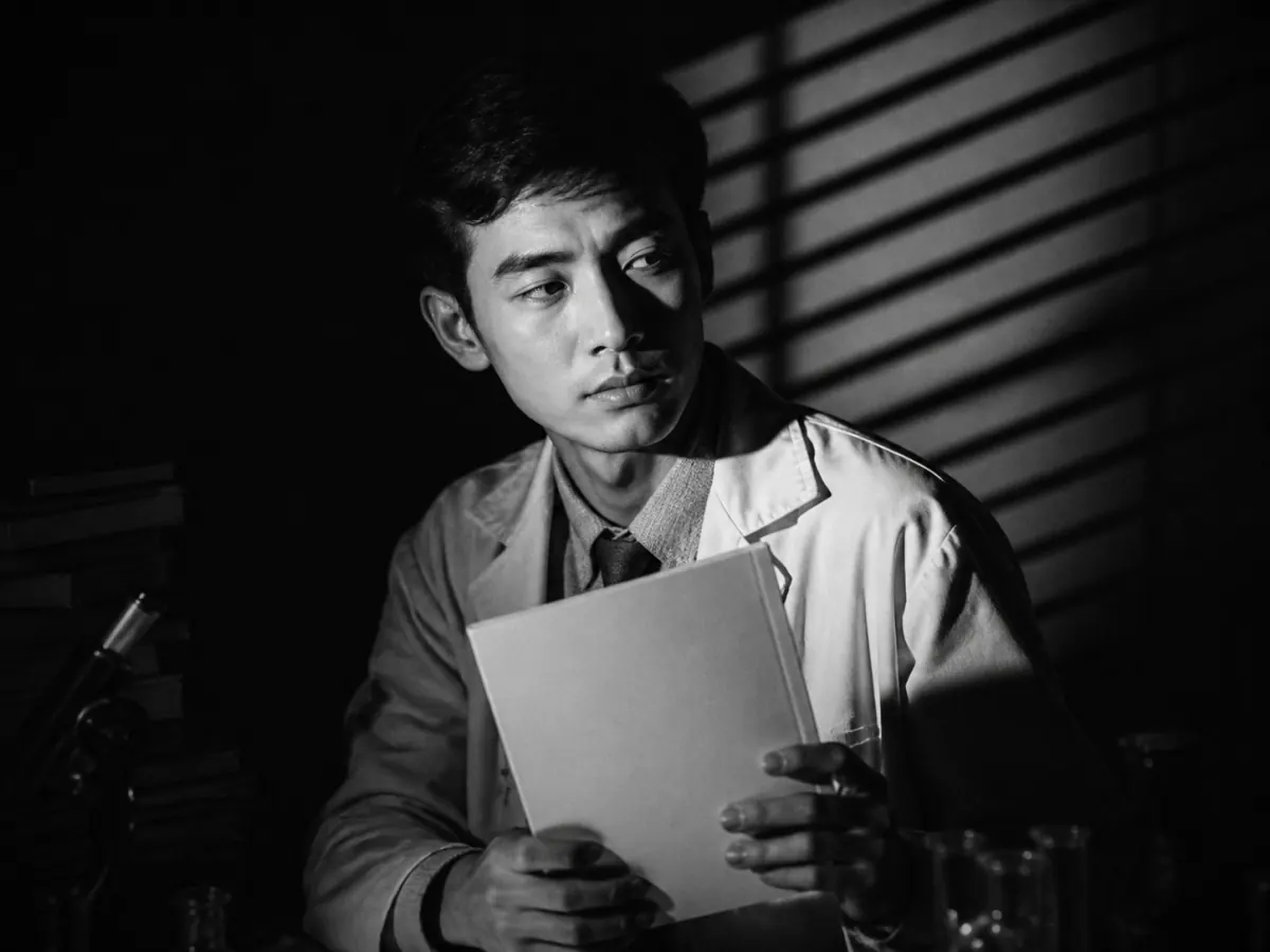 黑色电影低调摄影呈现的手持空白笔记本的青年研究者半身像